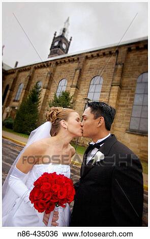 Young married couple kissing outside of church View Large Photo Image Stock Photograph - Young married couple kissing outside of church. Fotosearch