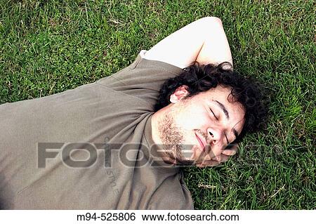 Stock Photograph - Young men resting on grass. Fotosearch