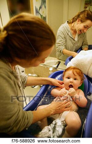 Stock Photograph - Young mother bathing 6 month old infant. Fotosearch