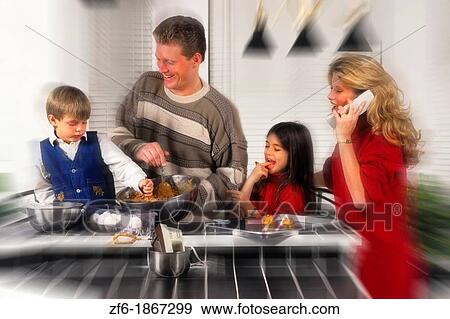 Young mother in her 30s on phone while she and husband help her two children make cookies in the home kitchen View Large Photo Image Stock Photo - Young mother in her 30s on phone while she and husband help her two children make cookies in the home kitchen. Fotosearch