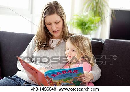 Young mother reading children book to his three year old daughter in the living room View Large Photo Image Stock Photo - Young mother reading children book to his three year old daughter in the living room. Fotosearch