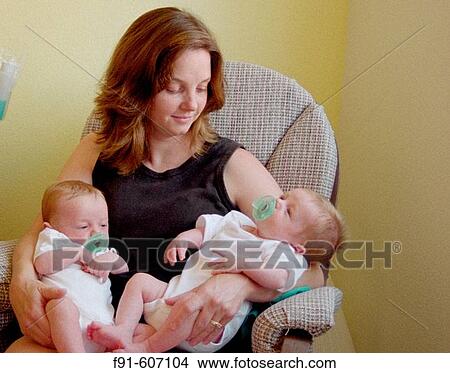 Young mother rocking twin boys to sleep View Large Photo Image Picture - Young mother rocking twin boys to sleep. Fotosearch
