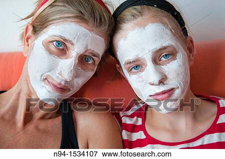 Stock Photo - Young mother with her daughter at the time of relaxation Using the free time for personal care Using a facial mask to clean skin of the face. Fotosearch
