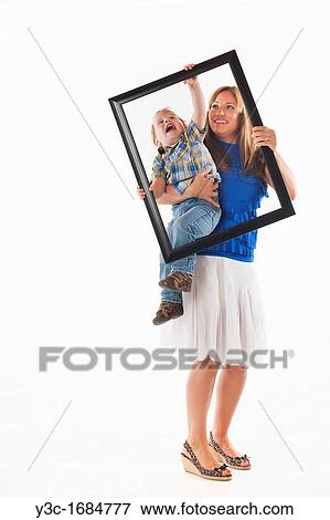 Stock Photo - Young mother with her toddler son trying to prepare for a portrait photograph involving a picture frame. Fotosearch