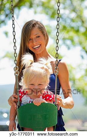 Young mother with two years old female child on a swing in a park View Large Photo Image Stock Image - Young mother with two years old female child on a swing in a park. Fotosearch