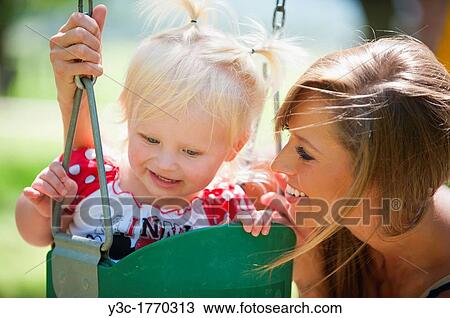 Young mother with two years old female child on a swing in a park View Large Photo Image Stock Image - Young mother with two years old female child on a swing in a park. Fotosearch
