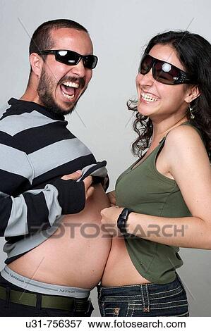 Stock Photo - Young newlywed couple wearing shades playing with their tummies. Fotosearch