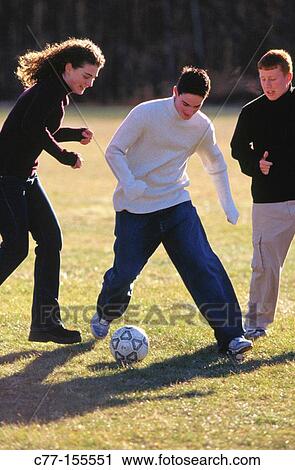 Stock Image - Young people playing football. Fotosearch