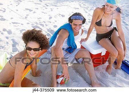 Stock Photo - Young people sitting at the beach. Fotosearch