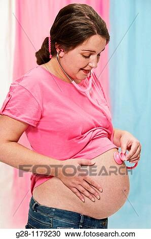 Young pregant woman in a pink top listening with a pink stethoscope to her protruding belly View Large Photo Image Stock Image - Young pregant woman in a pink top listening with a pink stethoscope to her protruding belly. Fotosearch