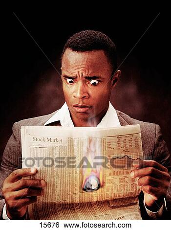 Stock Photograph - young professional African American male holding newspaper with hole. Fotosearch