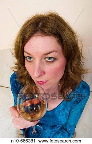 Young redhead woman sitting on her sofa, drinking a glass of wine. View Large Photo Image Stock Image - Young redhead woman sitting on her sofa, drinking a glass of wine.. Fotosearch