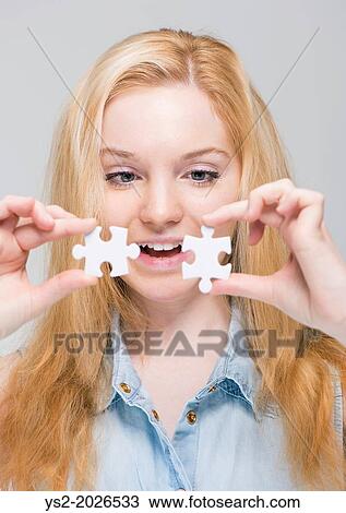 Young smiling blonde woman holding and examining two white puzzle pieces. View Large Photo Image Stock Image - Young smiling blonde woman holding and examining two white puzzle pieces.. Fotosearch