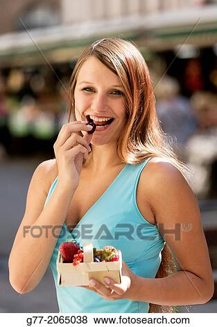 Young smiling woman eating fresh fruits art a market. Czech Republic. Prague. View Large Photo Image Stock Photo - Young smiling woman eating fresh fruits art a market. Czech Republic. Prague.. Fotosearch