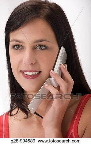 Stock Photo - young smiling woman in red using a telephone. Fotosearch