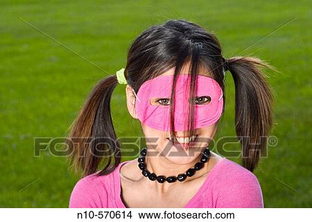 Young Spanish/Asian woman, in pigtails and a pink mask, posing at a park View Large Photo Image Picture - Young Spanish/Asian woman, in pigtails and a pink mask, posing at a park. Fotosearch