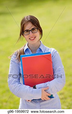Stock Image - Young student girl at the park with books.. Fotosearch