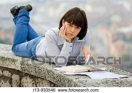 Young student woman is learning outdoors from a book and papers View Large Photo Image Stock Photograph - Young student woman is learning outdoors from a book and papers. Fotosearch