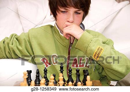 young teenage boy thinking in front of his chess game in a green sweater View Large Photo Image Stock Photo - young teenage boy thinking in front of his chess game in a green sweater. Fotosearch