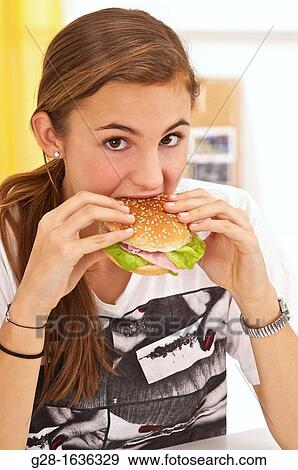 Stock Photo - Young teenage girl eating a hamburger with salad. Fotosearch