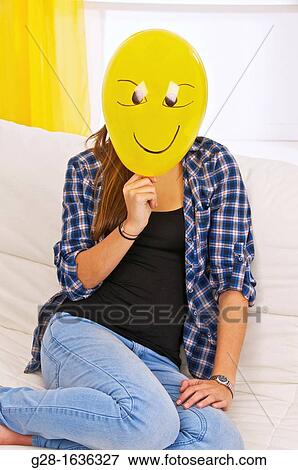Young teenage girl holding and hiding behind a yellow balloon with a smiling face drawn on it View Large Photo Image Stock Photo - Young teenage girl holding and hiding behind a yellow balloon with a smiling face drawn on it. Fotosearch