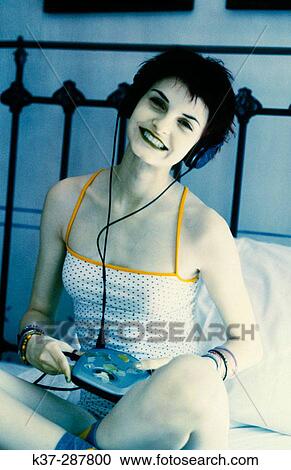 Stock Image - Young teenage woman listening to music on headphones and discman. Fotosearch