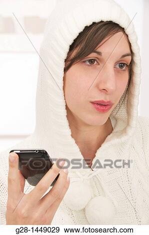 Young thoughtful woman in white woolen hood on her head, holding her phone in one hand View Large Photo Image Stock Photo - Young thoughtful woman in white woolen hood on her head, holding her phone in one hand. Fotosearch