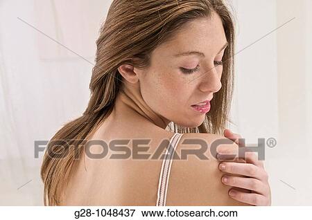 Stock Photo - young wman scratching her shoulder because of an itching sensation. Fotosearch