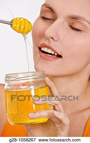 young woam holding a jar of liquid honey with eyes shut View Large Photo Image Stock Photo - young woam holding a jar of liquid honey with eyes shut. Fotosearch