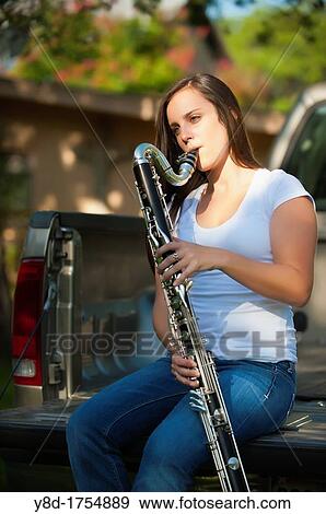 Young woman, 17 years caucasian, brunette hair, playing clarinet music instrument while sitting on the bed of a pickup truck View Large Photo Image Stock Photo - Young woman, 17 years caucasian, brunette hair, playing clarinet music instrument while sitting on the bed of a pickup truck. Fotosearch