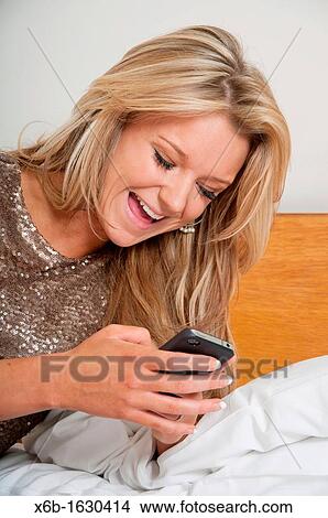 Young woman, 18-25 years, using smartphone in a hotel room View Large Photo Image Picture - Young woman, 18-25 years, using smartphone in a hotel room. Fotosearch