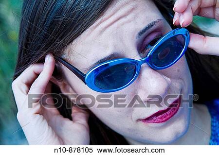 Stock Photography - Young woman adjusting her sunglasses.. Fotosearch