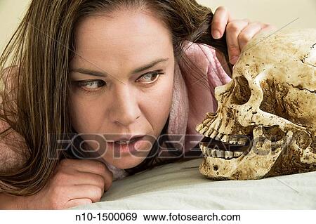 Stock Photo - Young woman and a fake human skull. Fotosearch