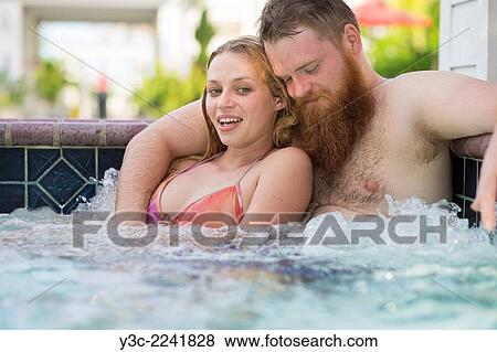 Stock Photo - Young woman and bearded man enjoying a bath in a hot tub pool.. Fotosearch