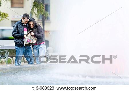 Young woman and water fountain, they are looking for something in her purse View Large Photo Image Stock Image - Young woman and water fountain, they are looking for something in her purse. Fotosearch