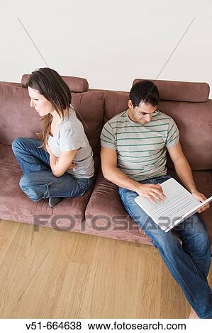 Young woman angry while her partner enjoys his laptop. View Large Photo Image Stock Photo - Young woman angry while her partner enjoys his laptop.. Fotosearch