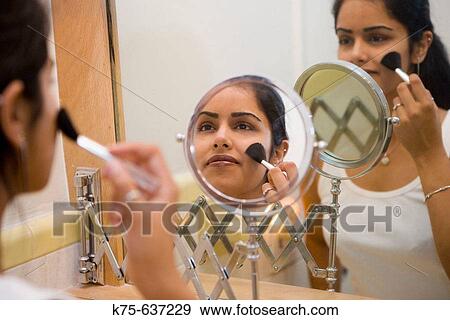 Young woman applying make-up in mirror View Large Photo Image Stock Photo - Young woman applying make-up in mirror. Fotosearch