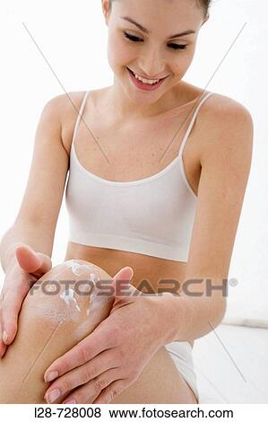 Stock Photo - young woman applying moisturizer on her leg. Fotosearch