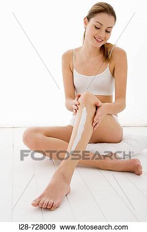 Stock Photo - young woman applying moisturizer on her leg. Fotosearch