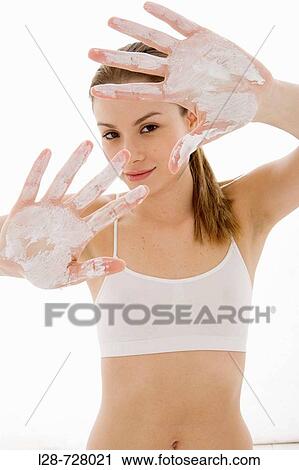 Stock Image - young woman applying moisturizer. Fotosearch