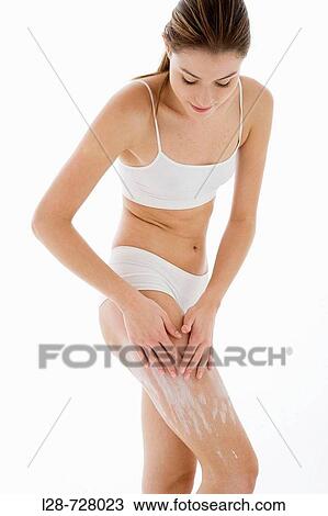 Stock Image - young woman applying moisturizer. Fotosearch