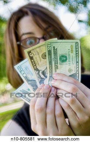 Young woman at a park, wearing glasses and holding up American money. View Large Photo Image Stock Image - Young woman at a park, wearing glasses and holding up American money.. Fotosearch