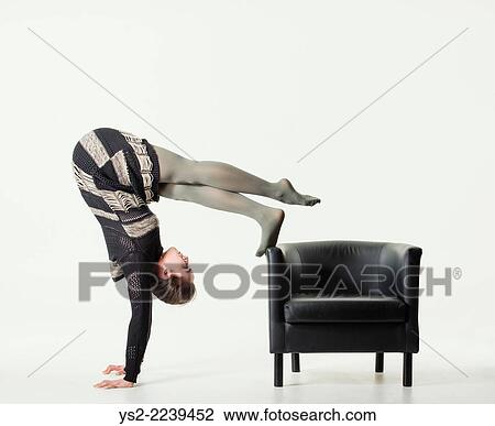 Young woman balancing on her hands and hold her foot on an empty leather chair. View Large Photo Image Stock Image - Young woman balancing on her hands and hold her foot on an empty leather chair.. Fotosearch