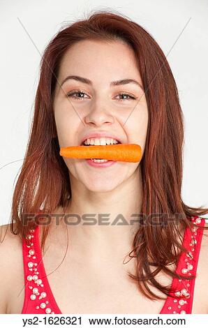 Young woman biting on an organic carrot View Large Photo Image Stock Image - Young woman biting on an organic carrot. Fotosearch