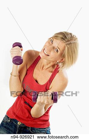 Stock Image - Young woman, blonde, exercising with weights in the gym to get fit.. Fotosearch
