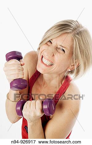 Young woman, blonde, exercising with weights in the gym to get fit. View Large Photo Image Stock Photo - Young woman, blonde, exercising with weights in the gym to get fit.. Fotosearch