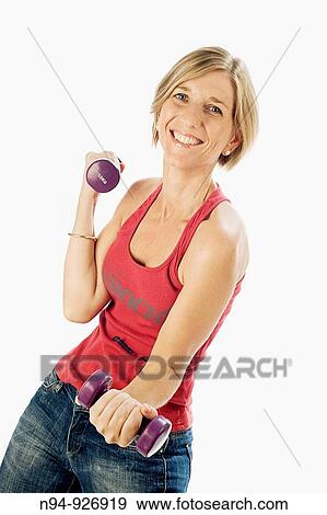 Young woman, blonde, exercising with weights in the gym to get fit. View Large Photo Image Stock Photo - Young woman, blonde, exercising with weights in the gym to get fit.. Fotosearch