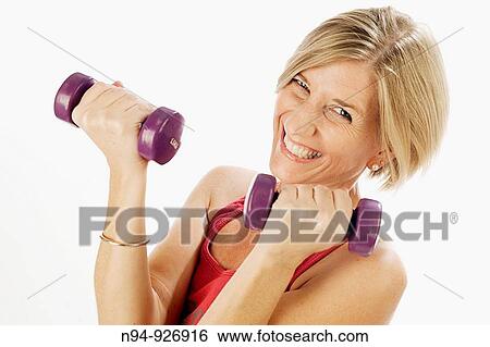 Young woman, blonde, exercising with weights in the gym to get fit. View Large Photo Image Stock Photograph - Young woman, blonde, exercising with weights in the gym to get fit.. Fotosearch
