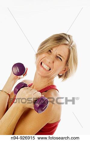 Stock Photography - Young woman, blonde, exercising with weights in the gym to get fit.. Fotosearch