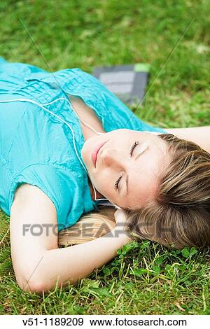 Stock Photo - Young woman blonde woman lying down on the park relaxing. Fotosearch